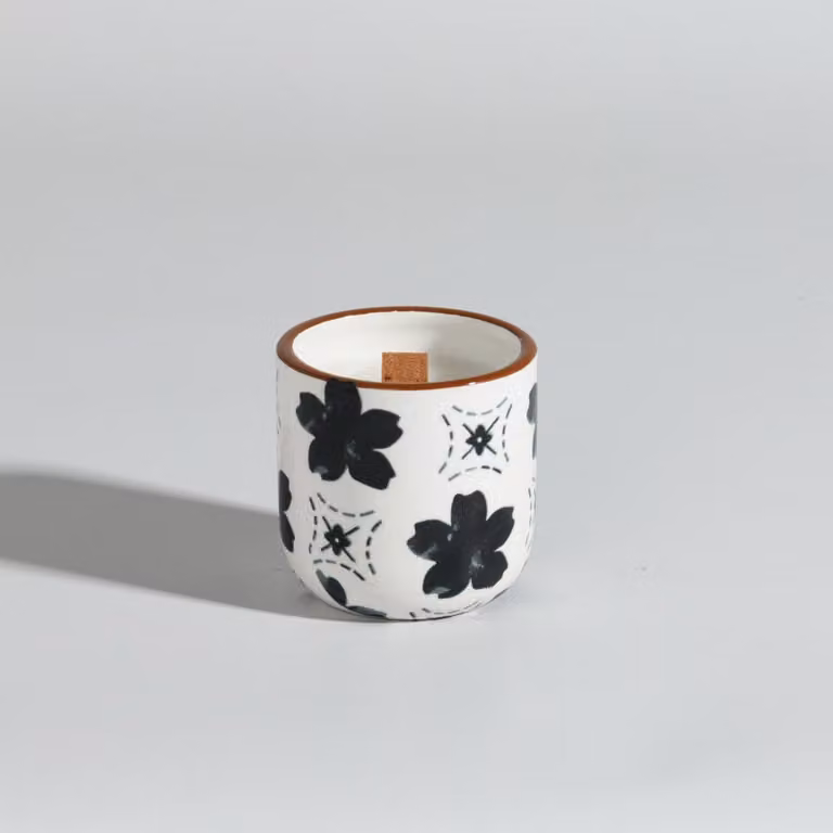 Vela perfumada de Maisons du Monde con aroma floral y gourmand en recipiente de cerámica beige y blanca de forma redonda