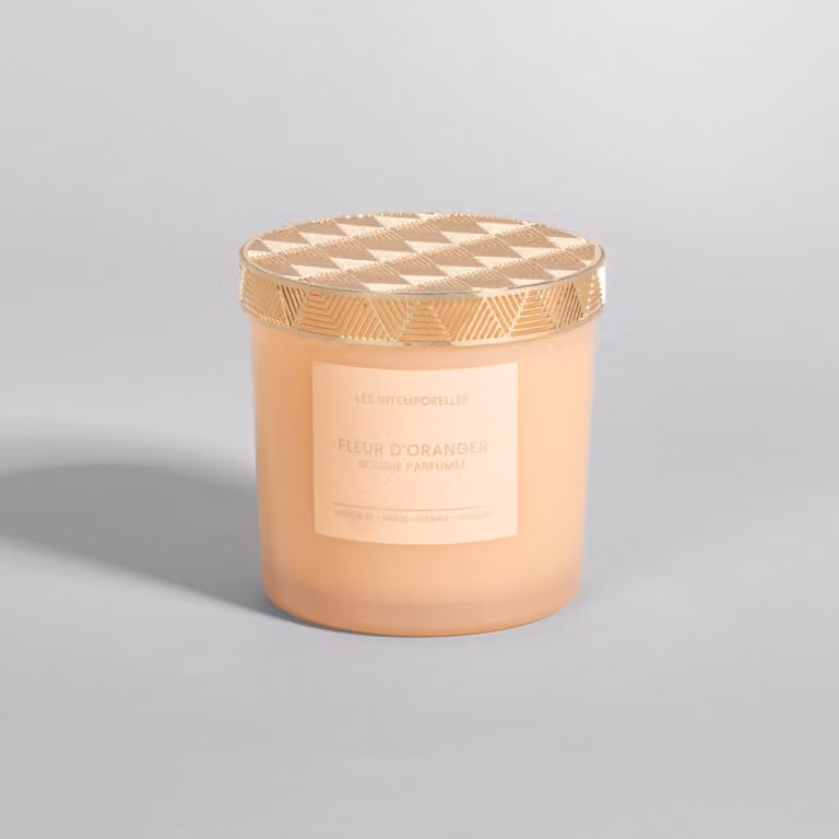 Vela perfumada LES INTEMPORELS de flor de azahar en colores naranja y dorado con diseño geométrico redondo para mesa